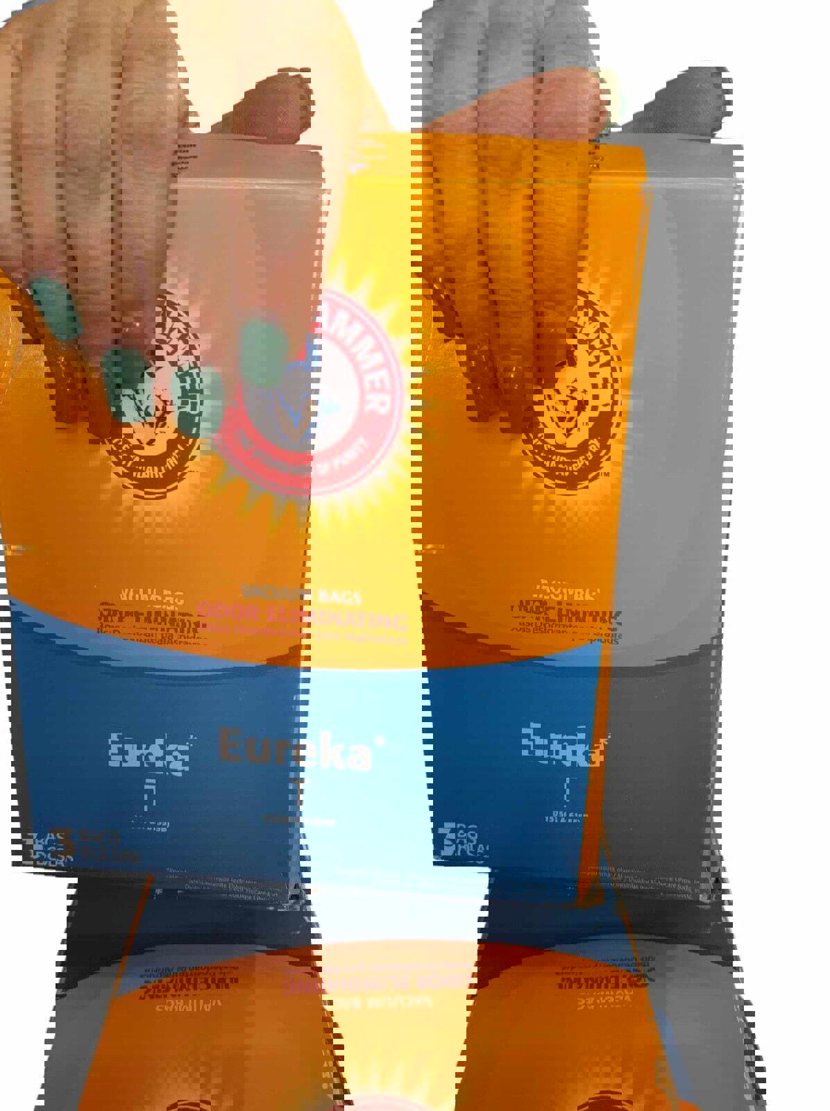 Eureka T odor eliminating bags in bright orange and blue packaging, held by a hand with green nails.