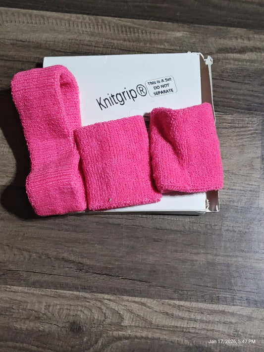 Knitgrip® pink wristbands in three sizes displayed on a wooden surface.
