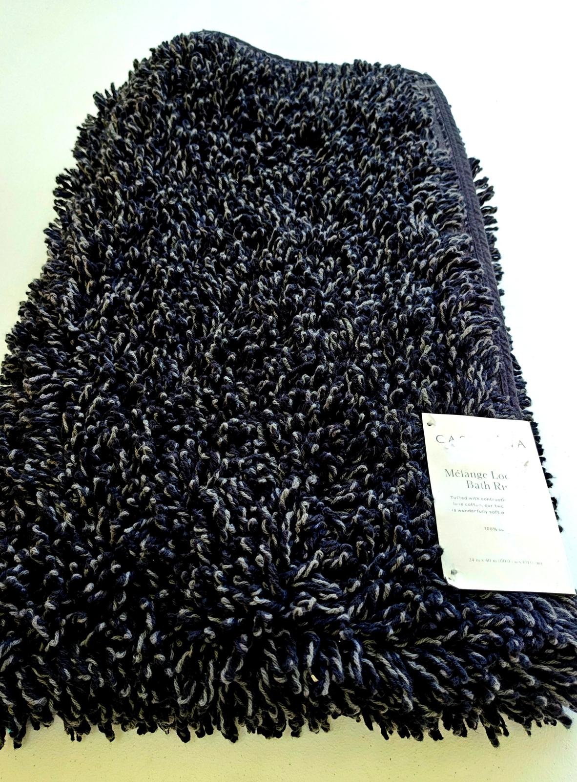 Black plush bath rug with soft texture and tag visible.