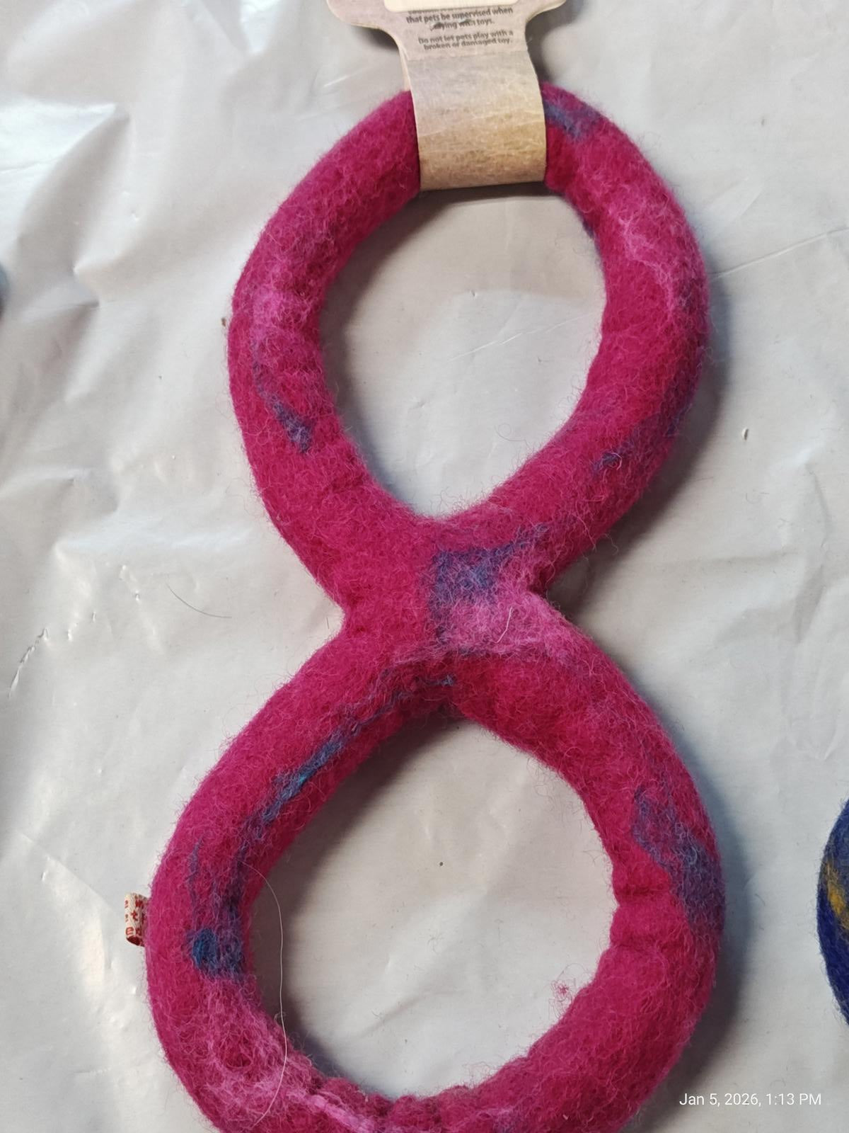 Pink felted wool toy shaped like the number eight, featuring a soft texture.