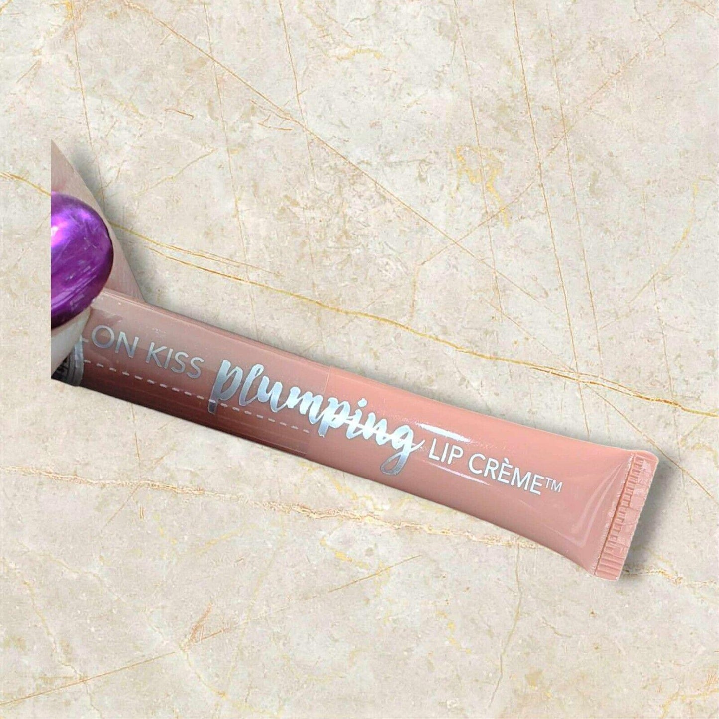 Kiss Plumping Lip Crème in a sleek tube with a glossy finish and purple cap.