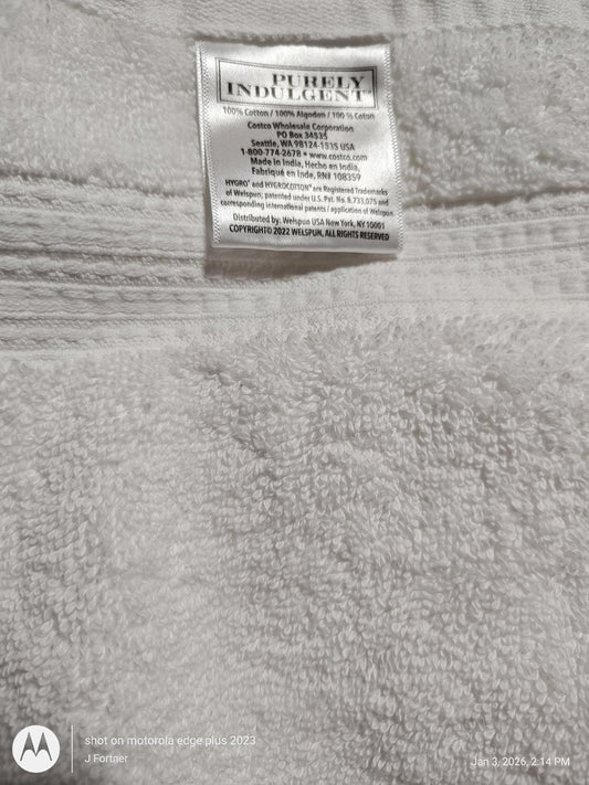 Purity Indulgence white bath towel with soft texture and care label.