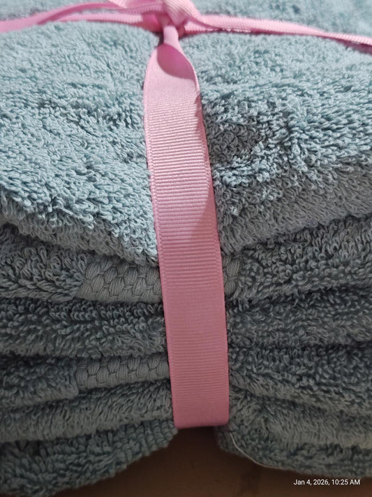 Soft blue bath towels neatly stacked and tied with a pink ribbon.