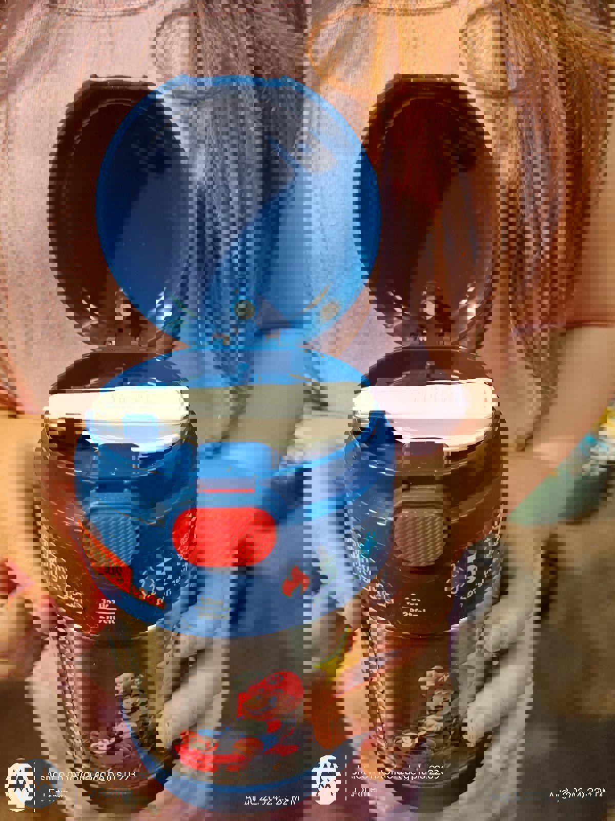 Super Mario themed container with a blue lid, held by a child, featuring 5 collectible pieces.