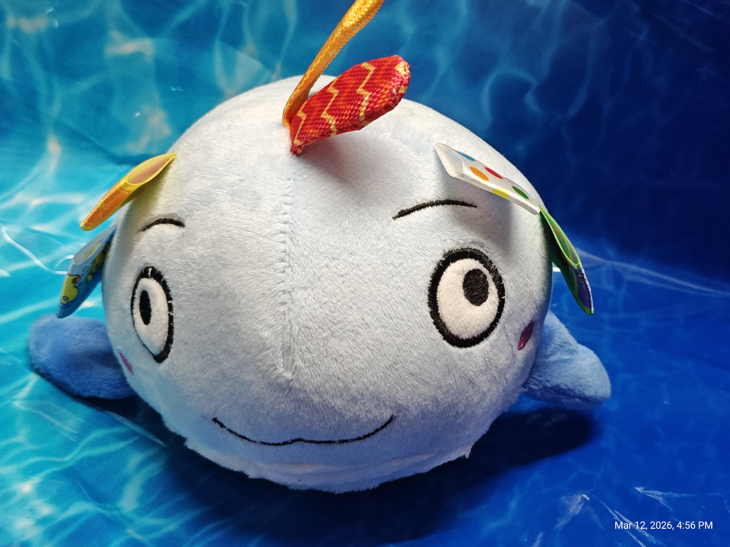 Whale plush toy with colorful tags and a smiling face, perfect for kids.