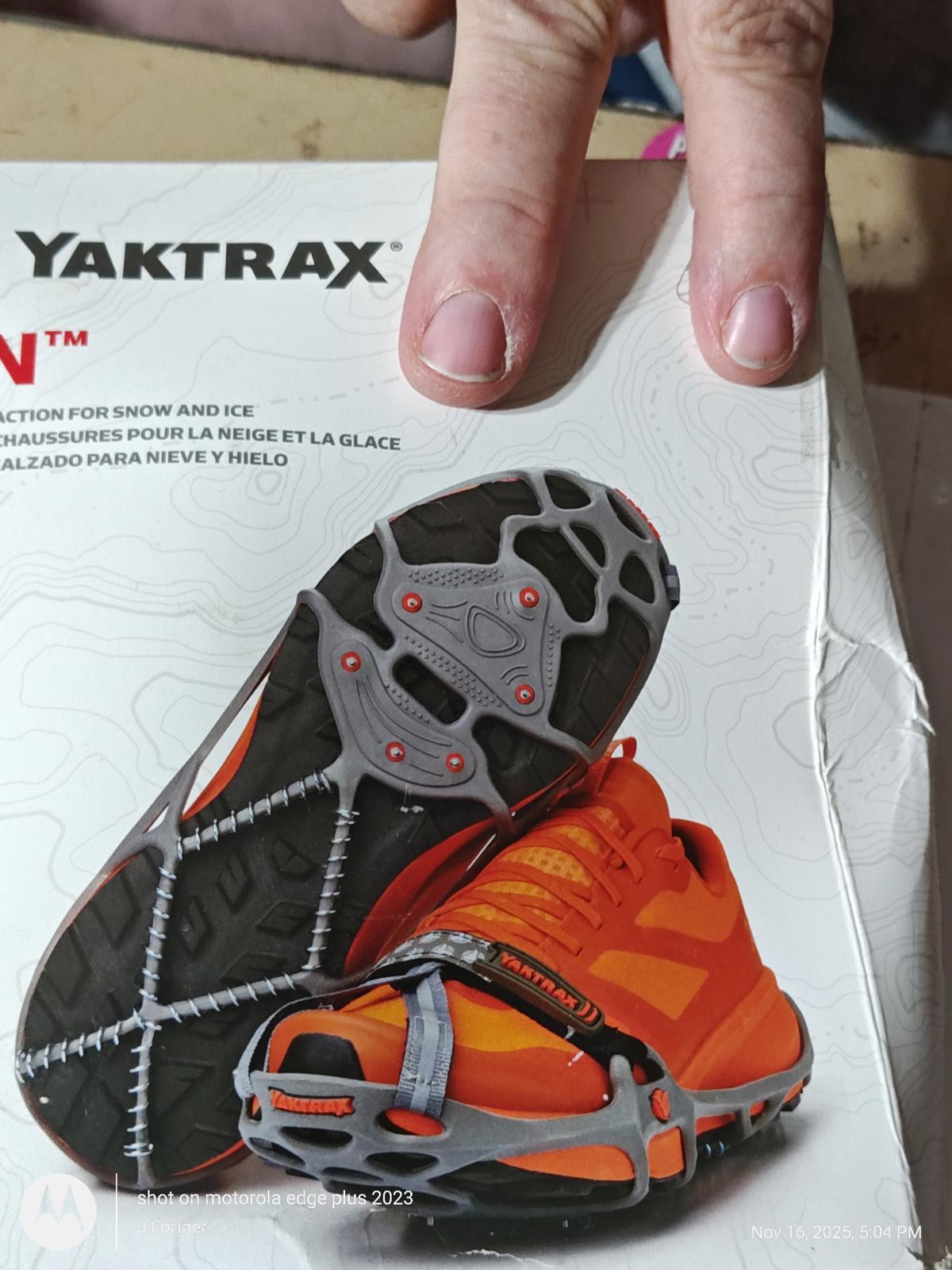 Yaktrax traction device for snow and ice, featuring a gray and orange design for enhanced grip.