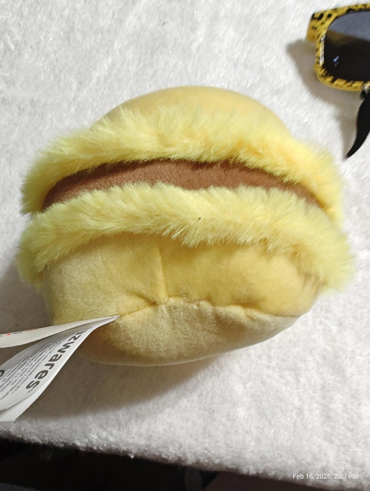 Yellow plush macaroon toy with fluffy texture and brown filling.