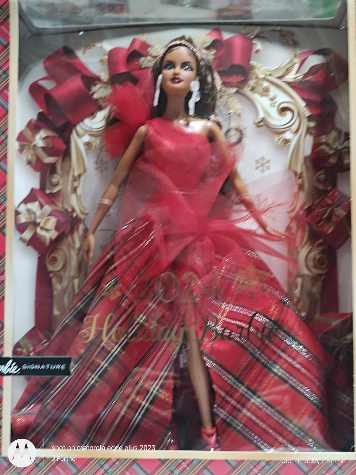 2023 Holiday Barbie in a stunning red gown with plaid accents and festive decorations.