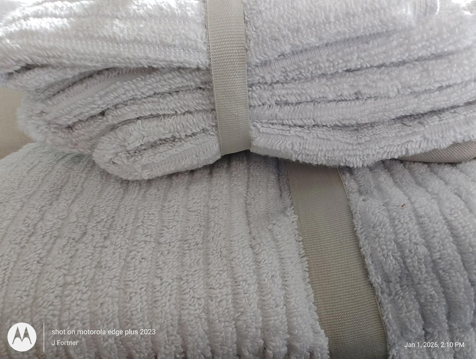 Soft white bath towels neatly stacked with bands for easy storage.