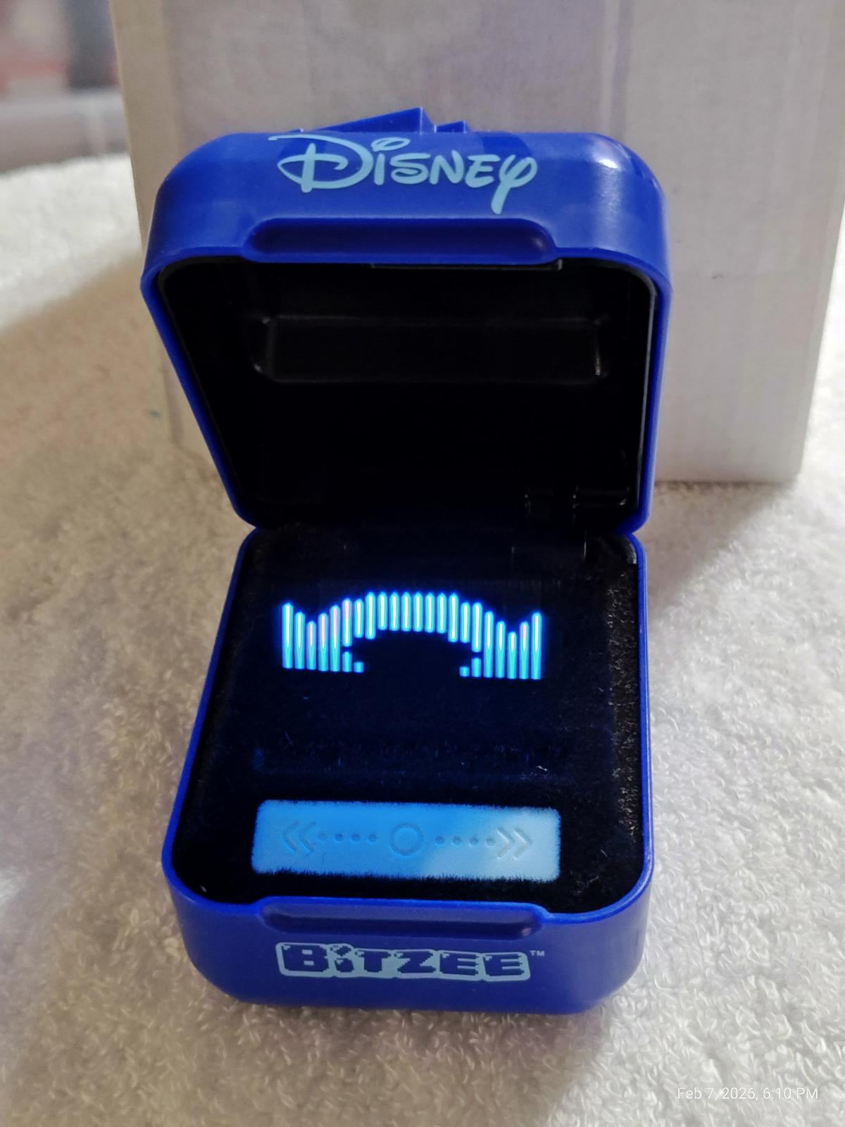 Bitzee Disney toy in blue case with glowing sound wave display.