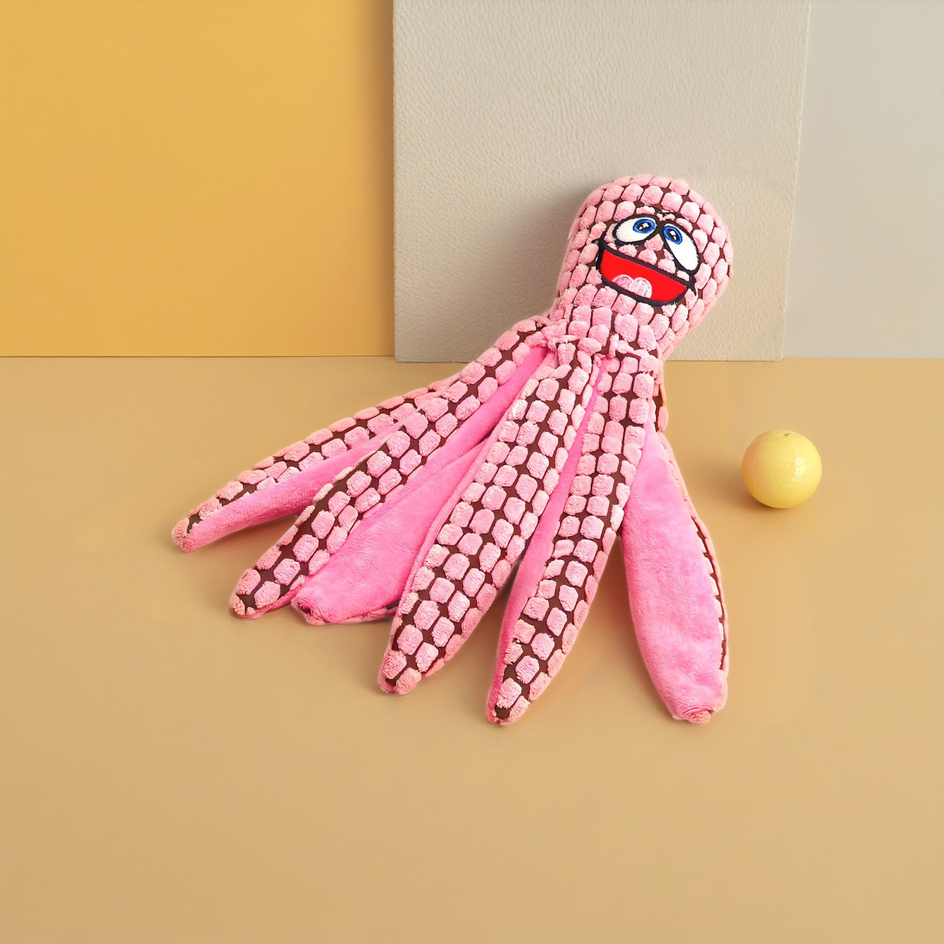 Pink octopus plush toy with a smiling face and textured tentacles.