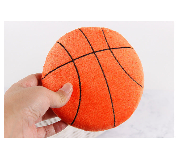 Basketball plush toy in hand, featuring bright orange color and black lines.
