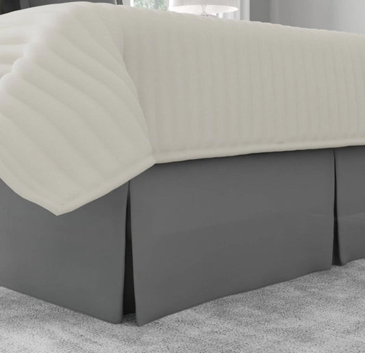 Bed skirt in gray color with a cream-colored quilted top layer.