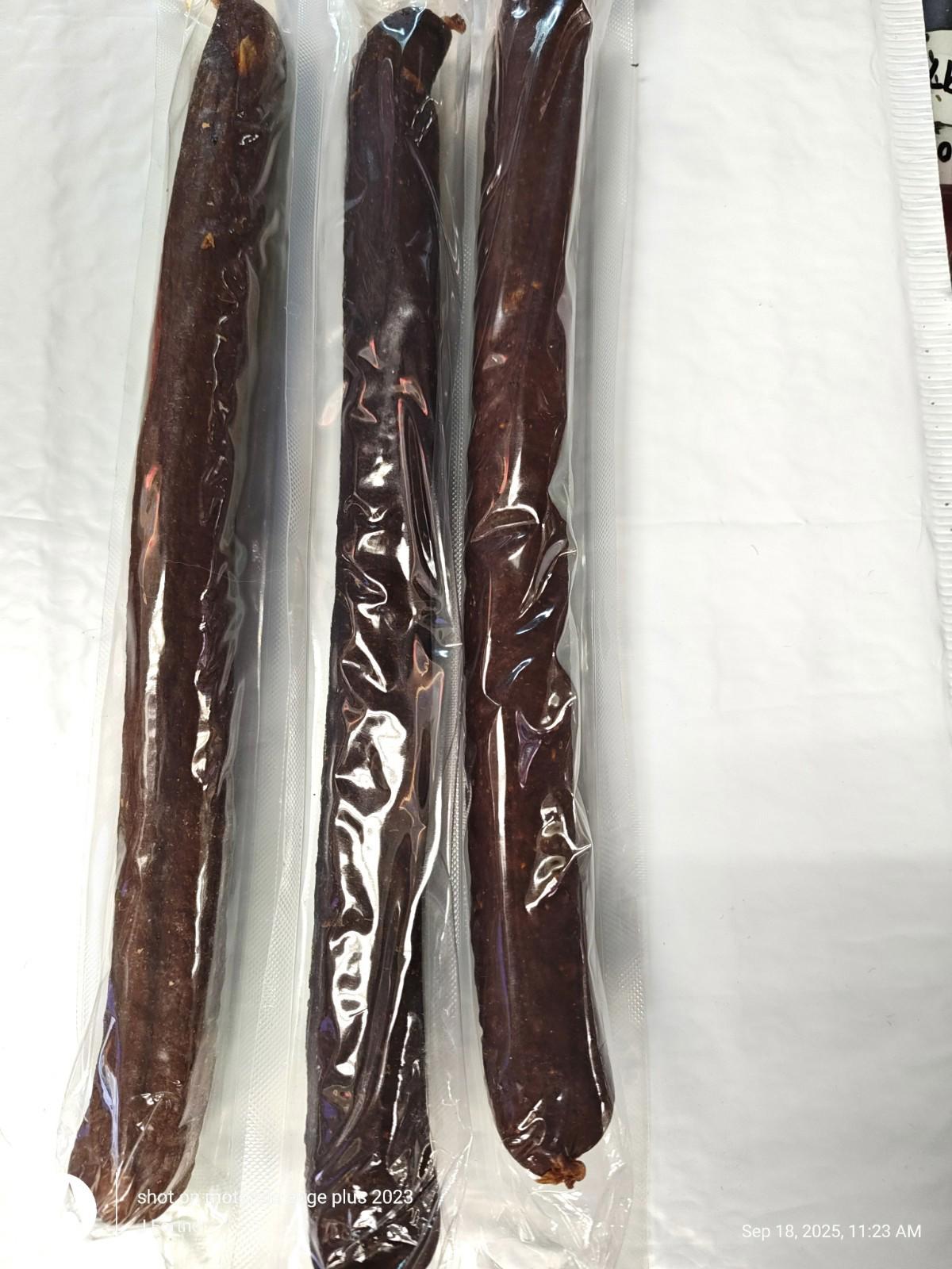 Beef Jerky Sticks in vacuum-sealed packaging, showcasing three long, dark brown sticks.