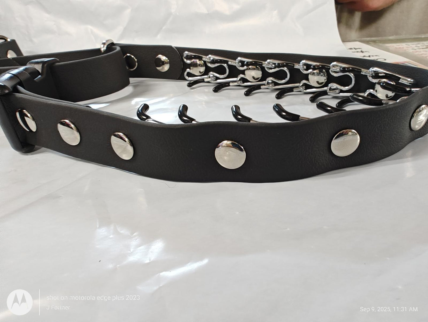 Black leather belt with silver studs and hooks for adjustable fit.