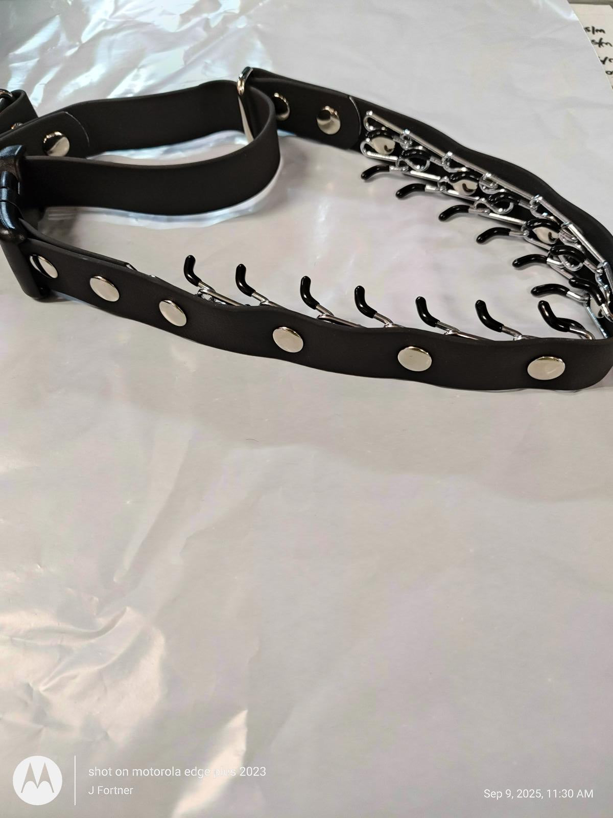 Black leather collar with silver studs and chain detailing.