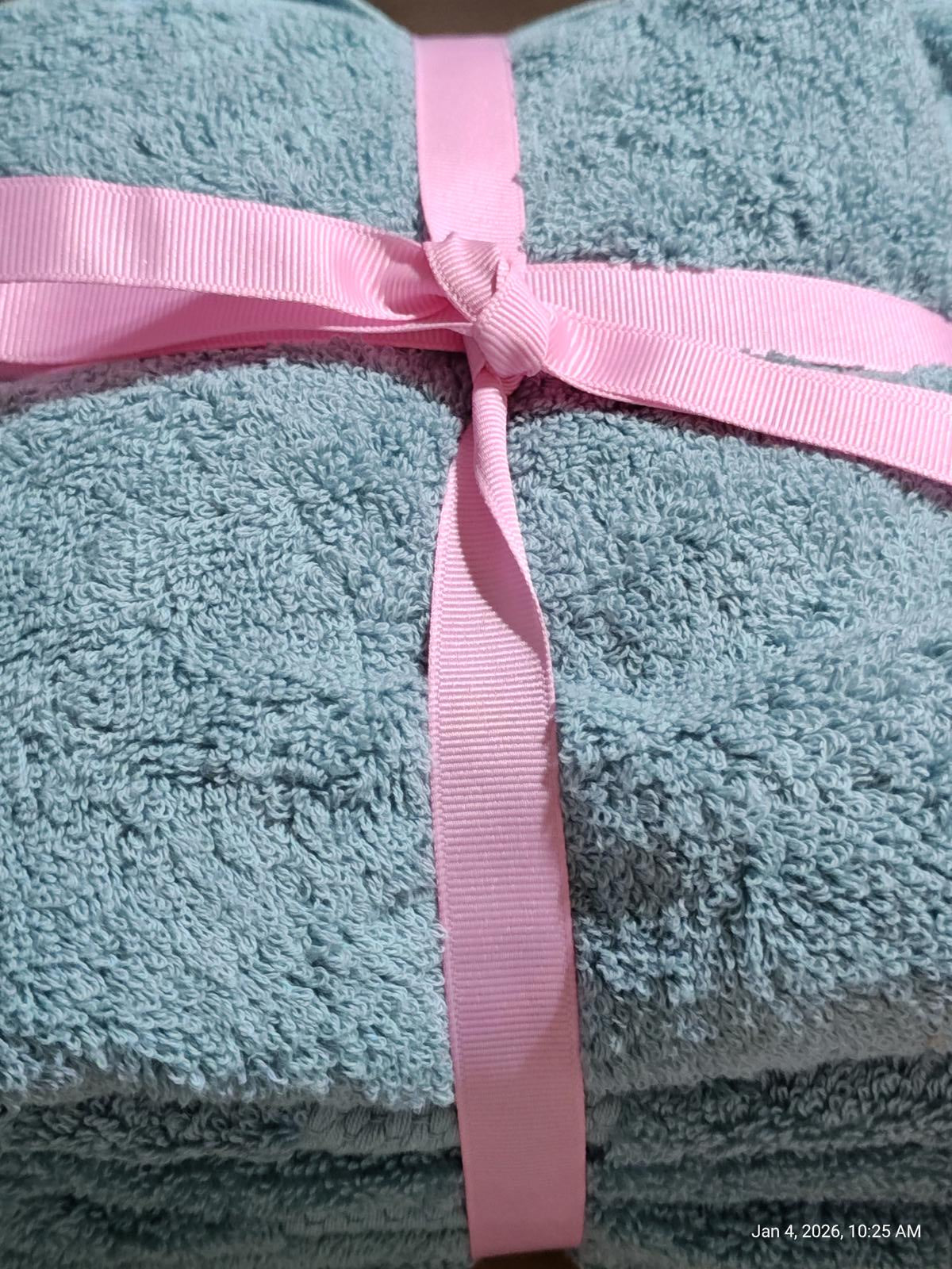 Soft teal bath towel set tied with a pink ribbon for a stylish presentation.