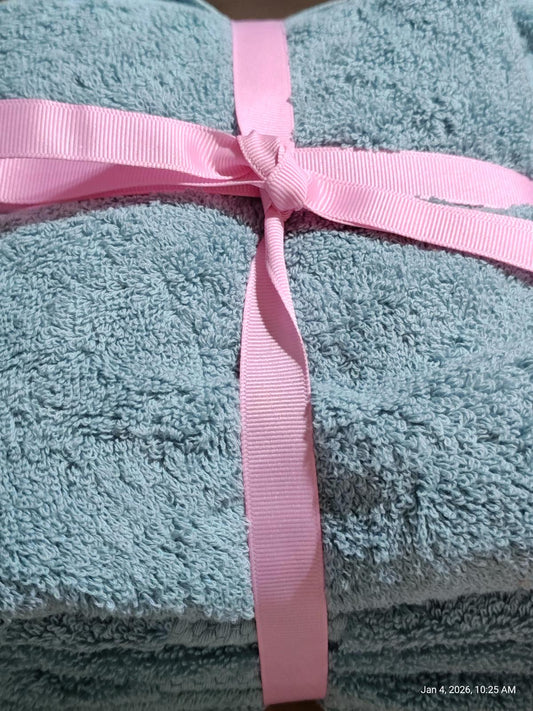 Soft teal bath towel set tied with a pink ribbon for a stylish presentation.