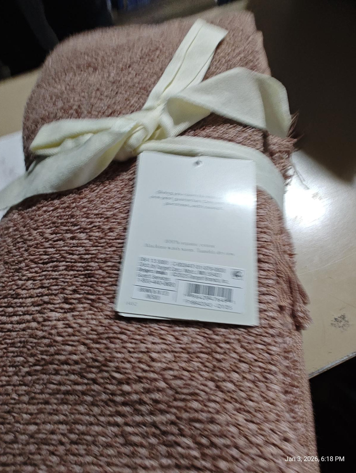 Soft blush bath towel with a ribbon, featuring a care label attached.