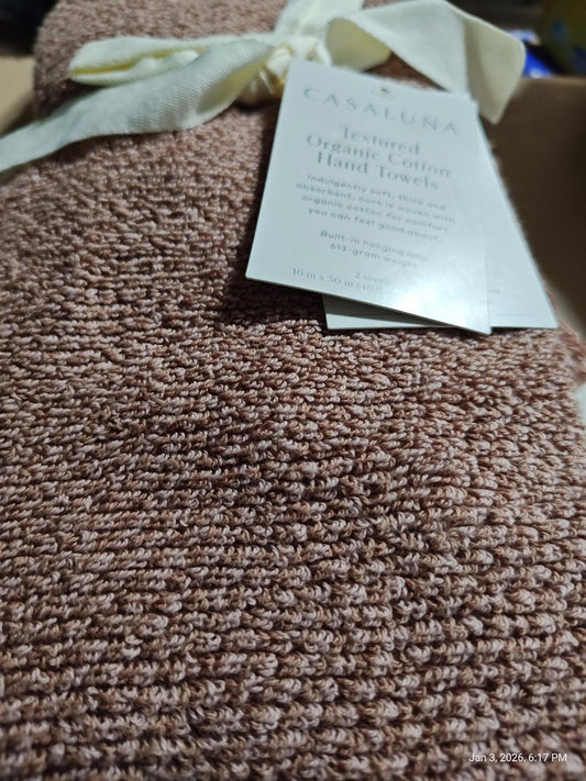 Casanova textured organic cotton hand towels in soft pink color, elegantly tied with a ribbon.