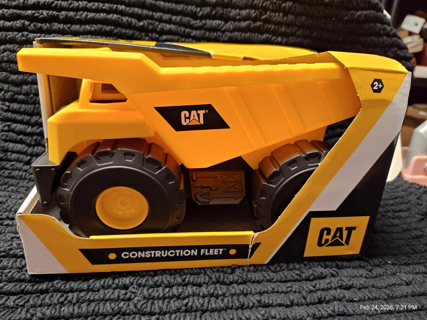CAT construction fleet toy truck in yellow and black packaging with large wheels.