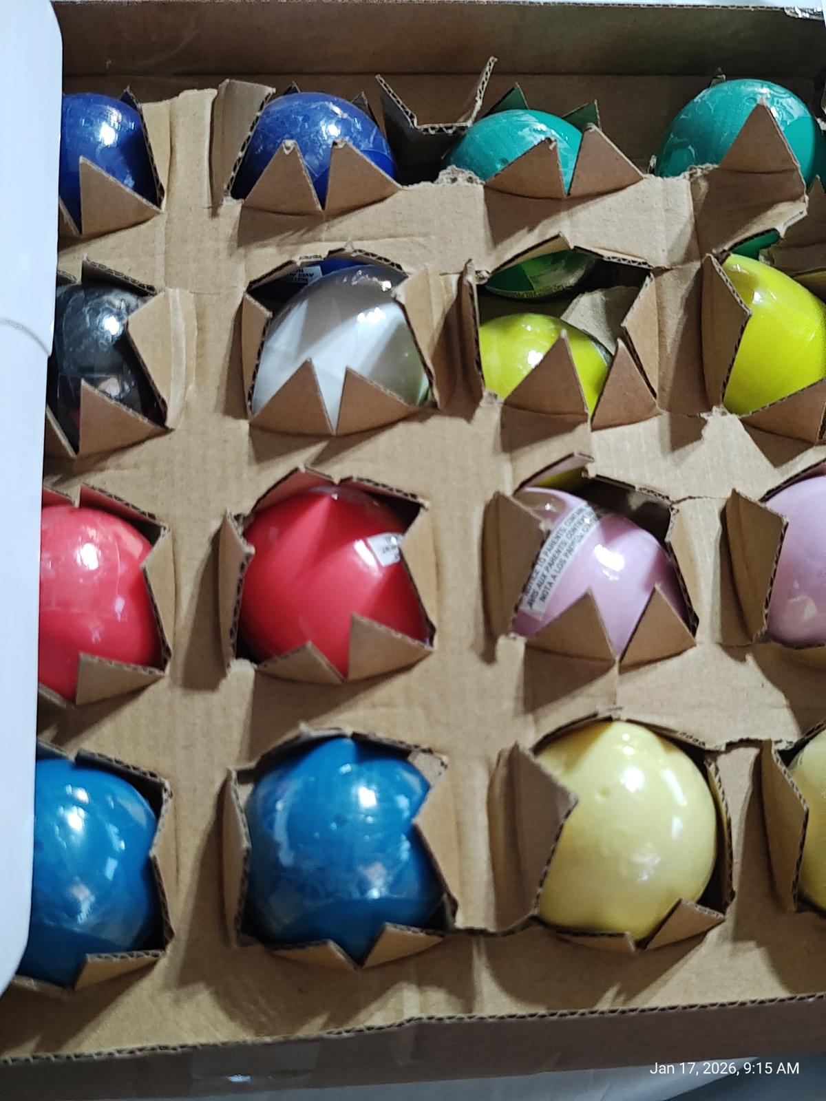 Colorful bouncy balls set in a cardboard box, featuring various vibrant colors and designs.