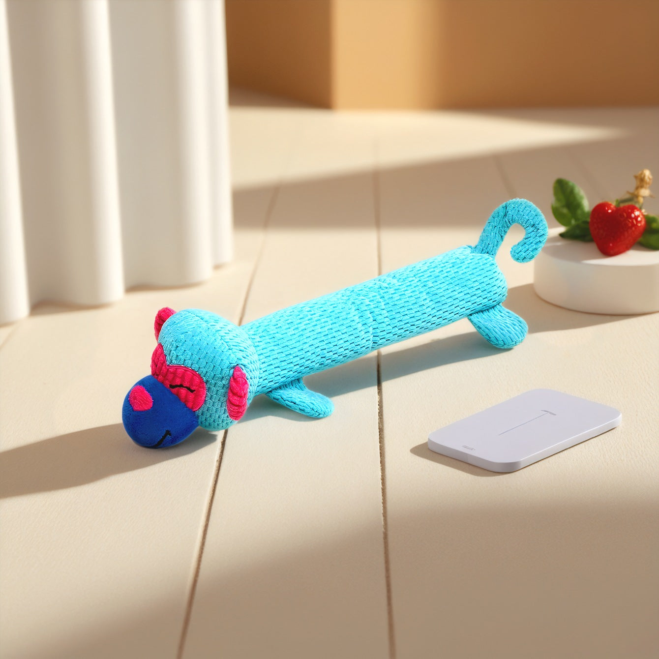Colorful monkey plush toy in blue and pink, lying on a wooden surface.