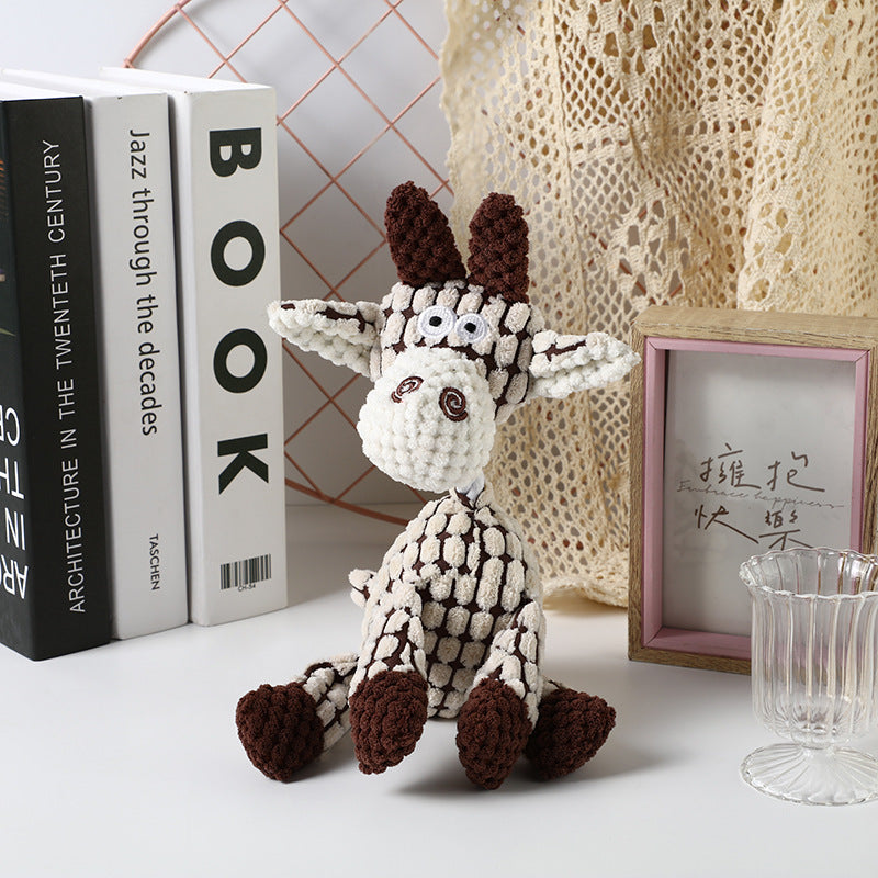 Crochet Giraffe Toy in brown and cream colors, sitting on a table with decorative items.