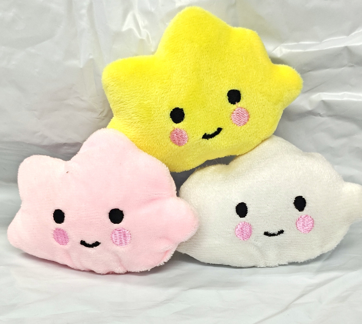 Cute plush cloud and star toys in yellow, pink, and white with smiling faces.