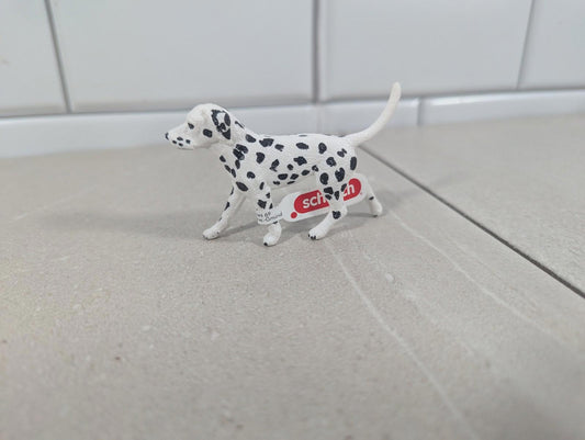 Dalmatian dog figurine with black spots, standing on a light surface.