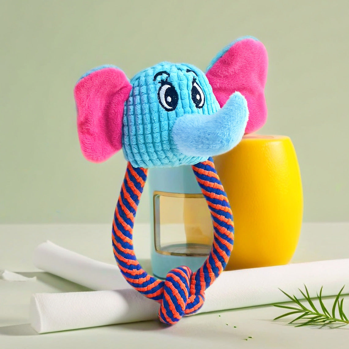 Elephant plush toy with blue and pink colors, featuring a smiling face and a rope handle.