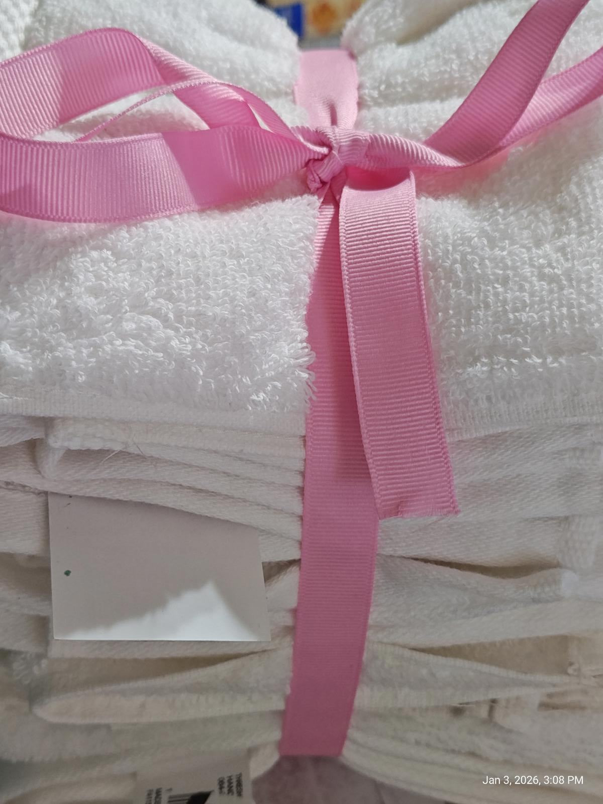 White bath towels neatly stacked and tied with a pink ribbon.