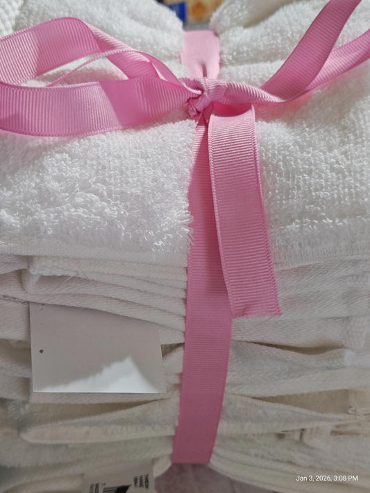 White bath towels neatly stacked and tied with a pink ribbon.
