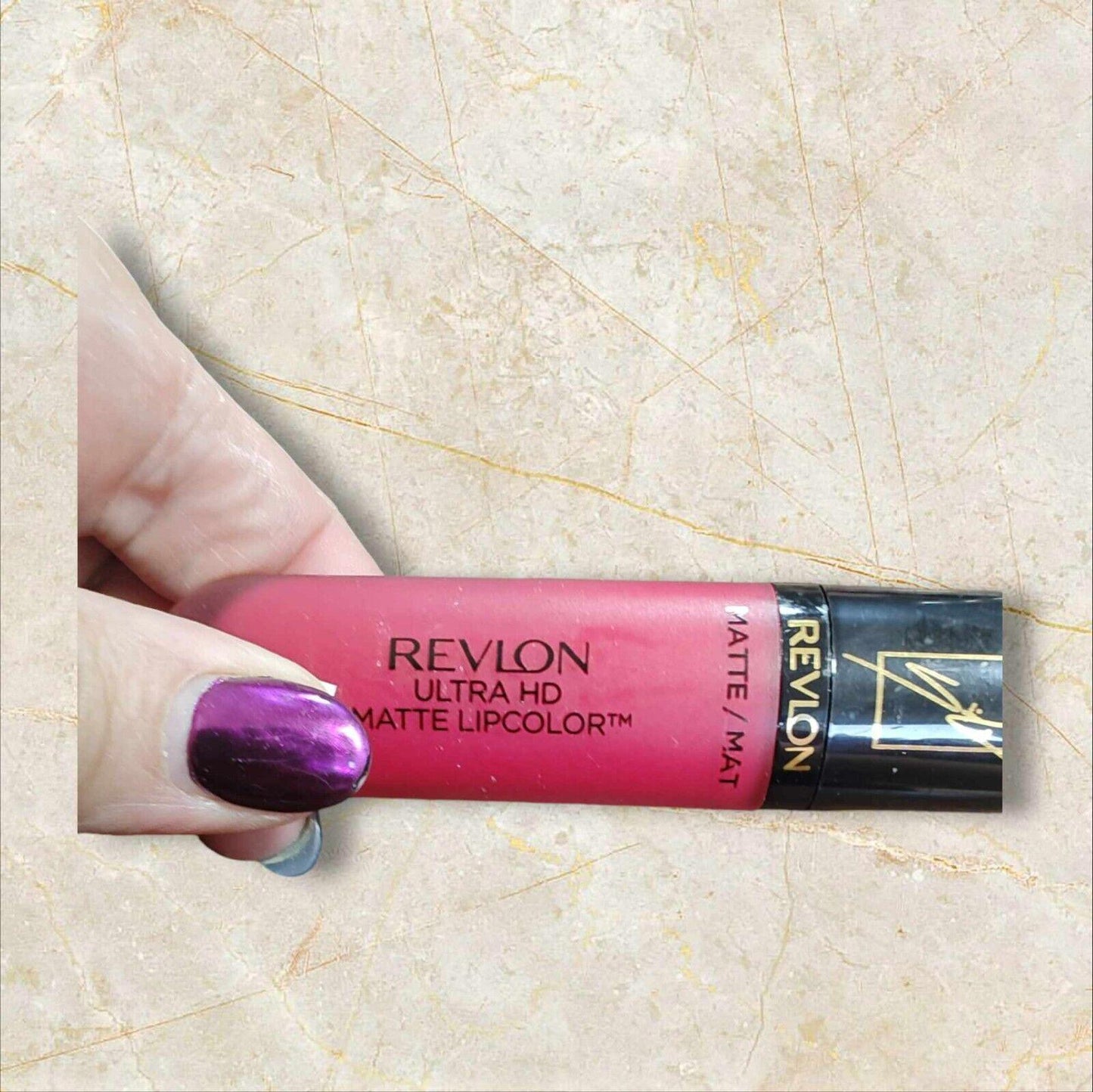 Revlon Ultra HD Matte Lipcolor in a vibrant pink shade held in hand.