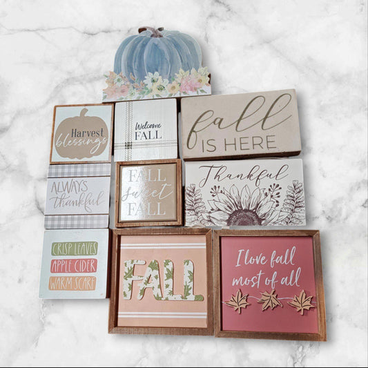 Fall decor signs featuring autumn themes and colors, including 'Fall is Here' and 'I love fall most of all.'