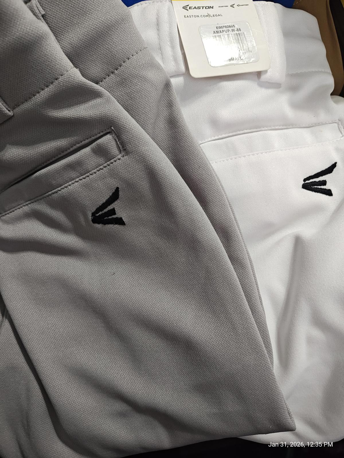 Gray and white golf pants featuring a stylish logo on the back pocket.