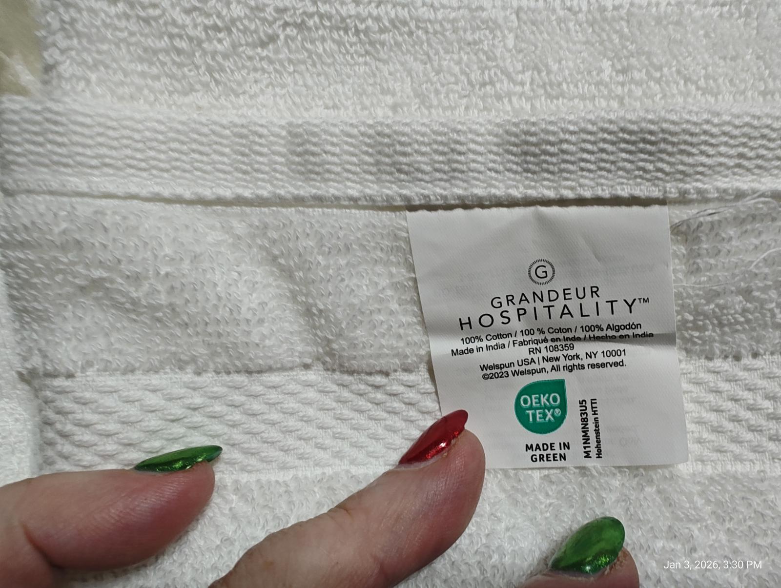 Grandeur Hospitality white towel with textured design and label.