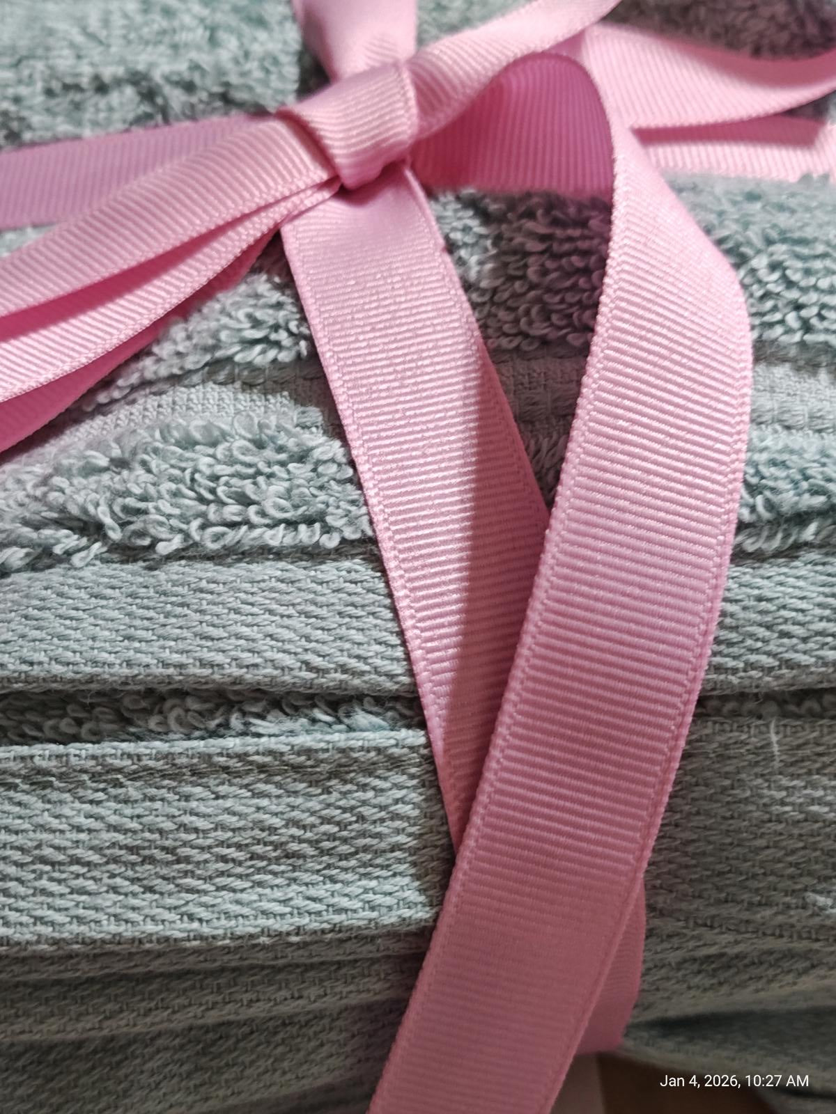Soft gray bath towels neatly stacked and tied with a pink ribbon.