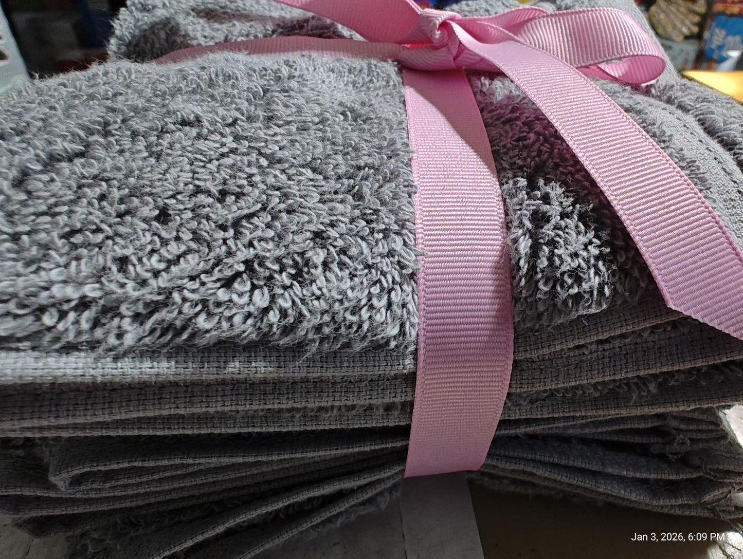 Gray bath towels set tied with a pink ribbon, showcasing soft texture and plush design.