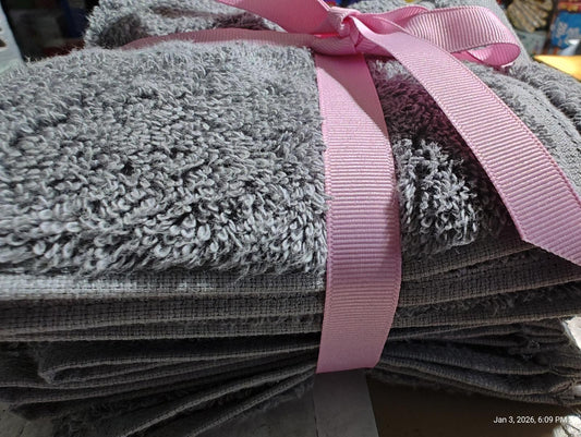 Gray bath towels set tied with a pink ribbon, showcasing soft texture and plush design.