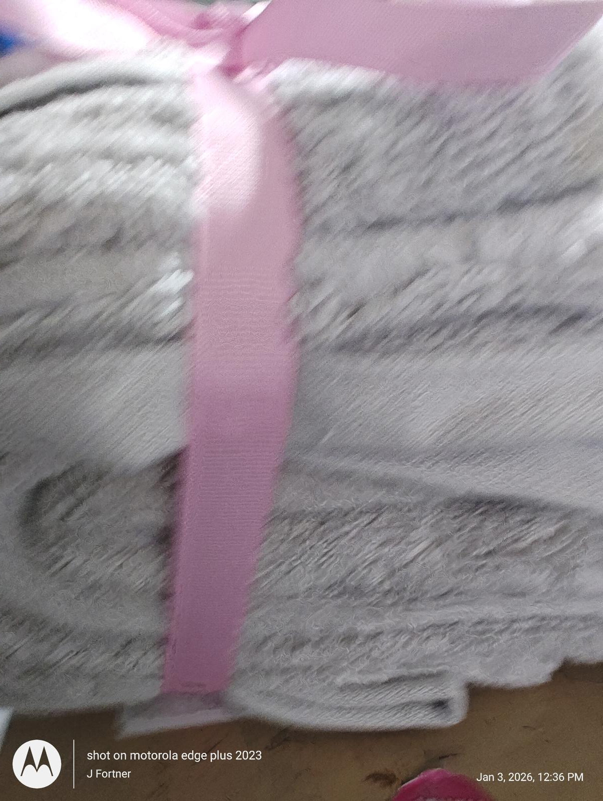 Soft gray bath towels neatly stacked with a pink ribbon.