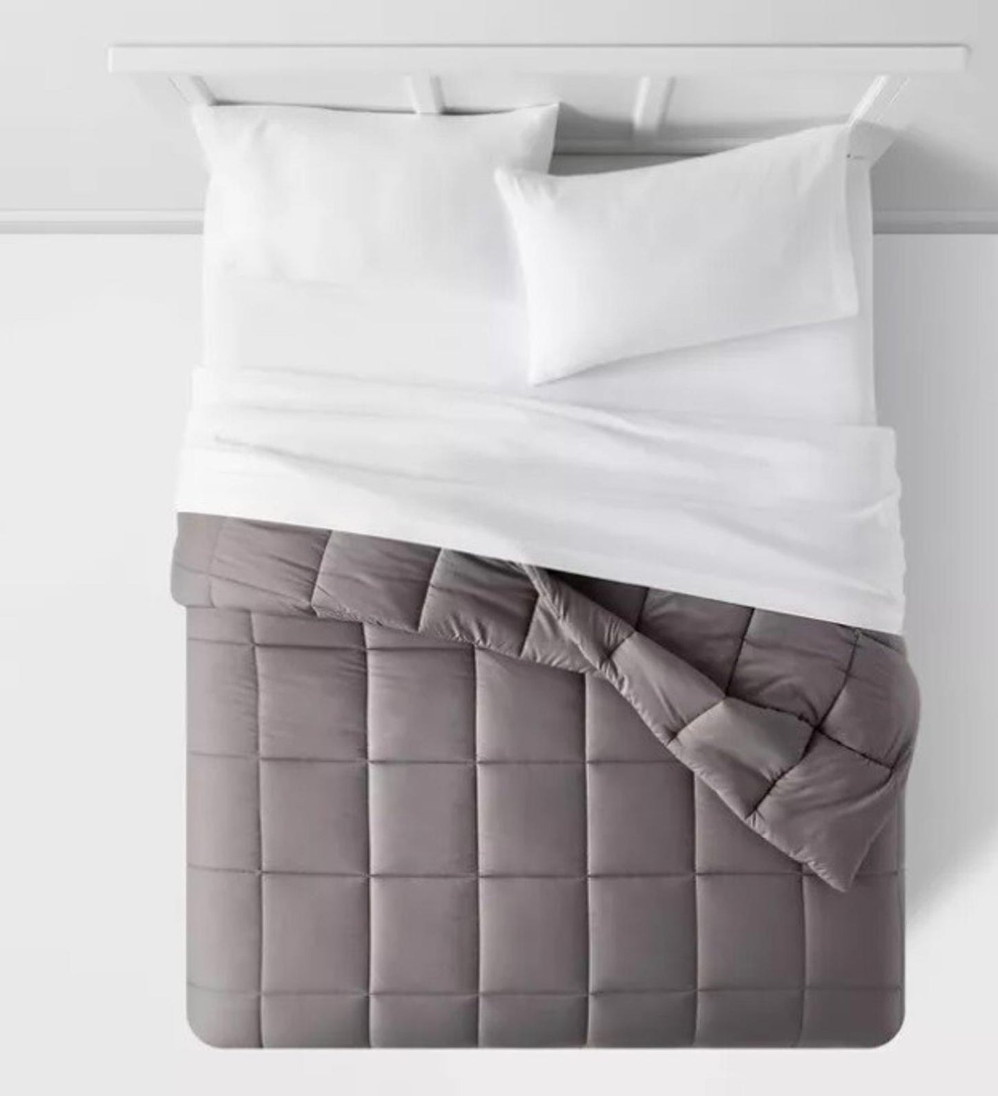 Gray quilted bedspread with white bedding on a neatly made bed.