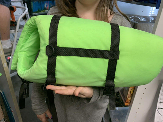 Green sleeping bag with black straps held by a person, ideal for camping and outdoor adventures.