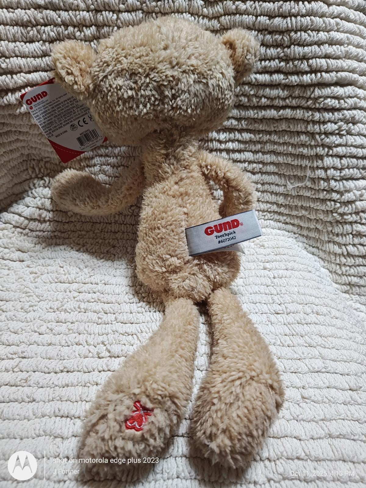 Gund plush toy with soft beige fur and long limbs, featuring a tag on its ear.