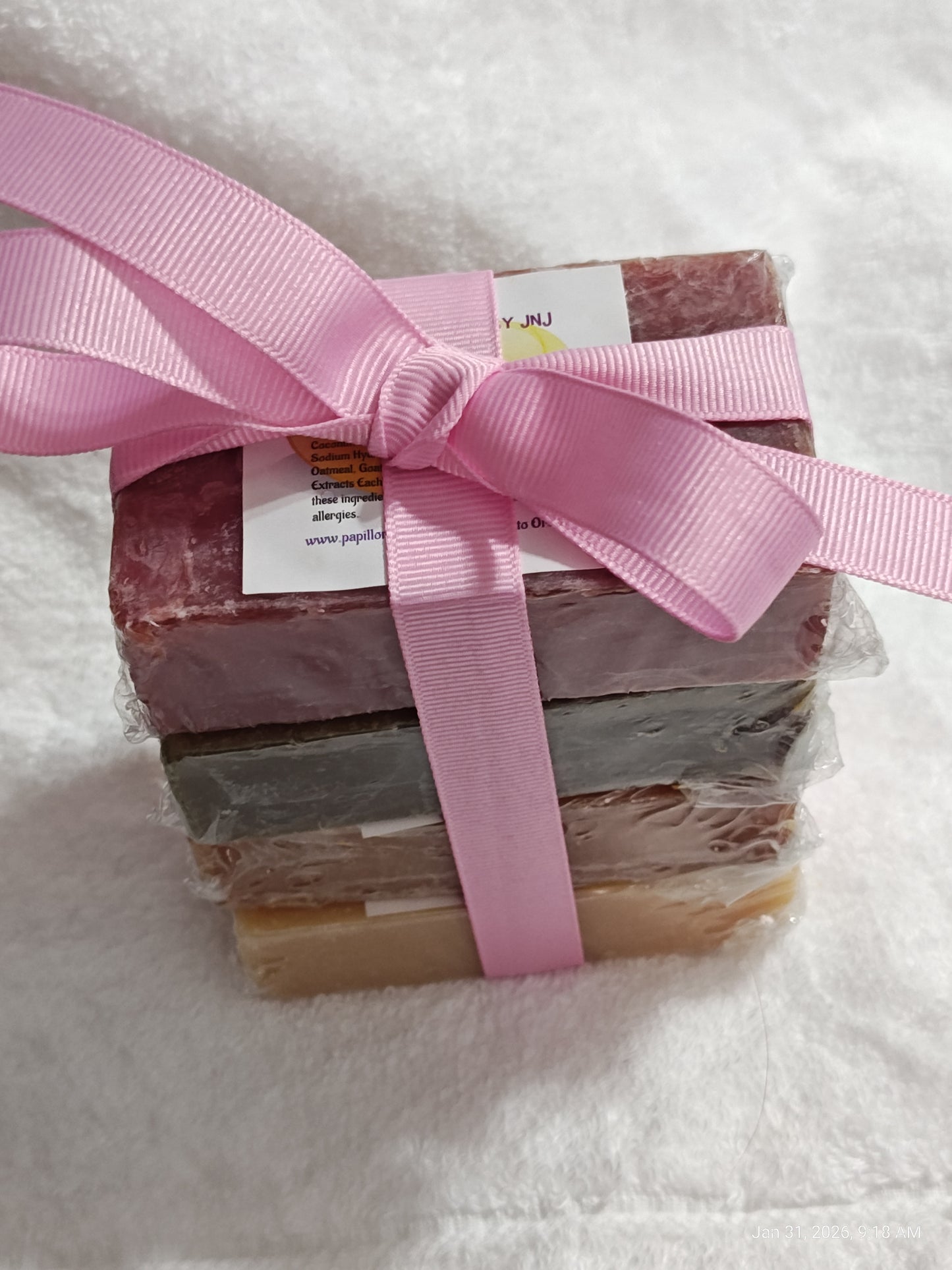 Handmade soap gift set with pink ribbon, featuring four colorful bars stacked together.