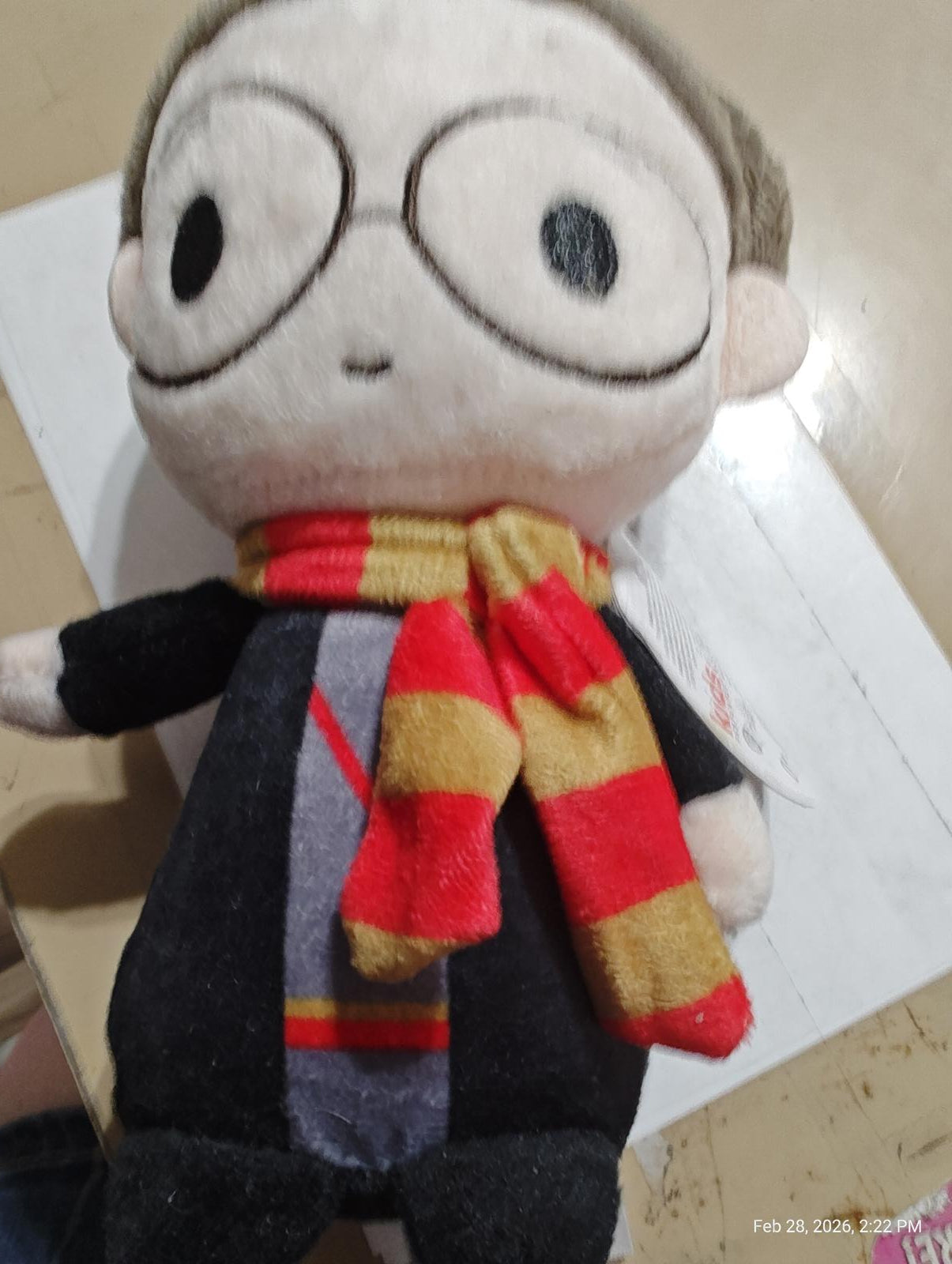 Harry Potter plush toy wearing a red and yellow scarf, featuring round glasses and a black robe.