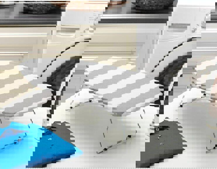 Ironing board cover with gray and white stripes, designed for compact ironing spaces.