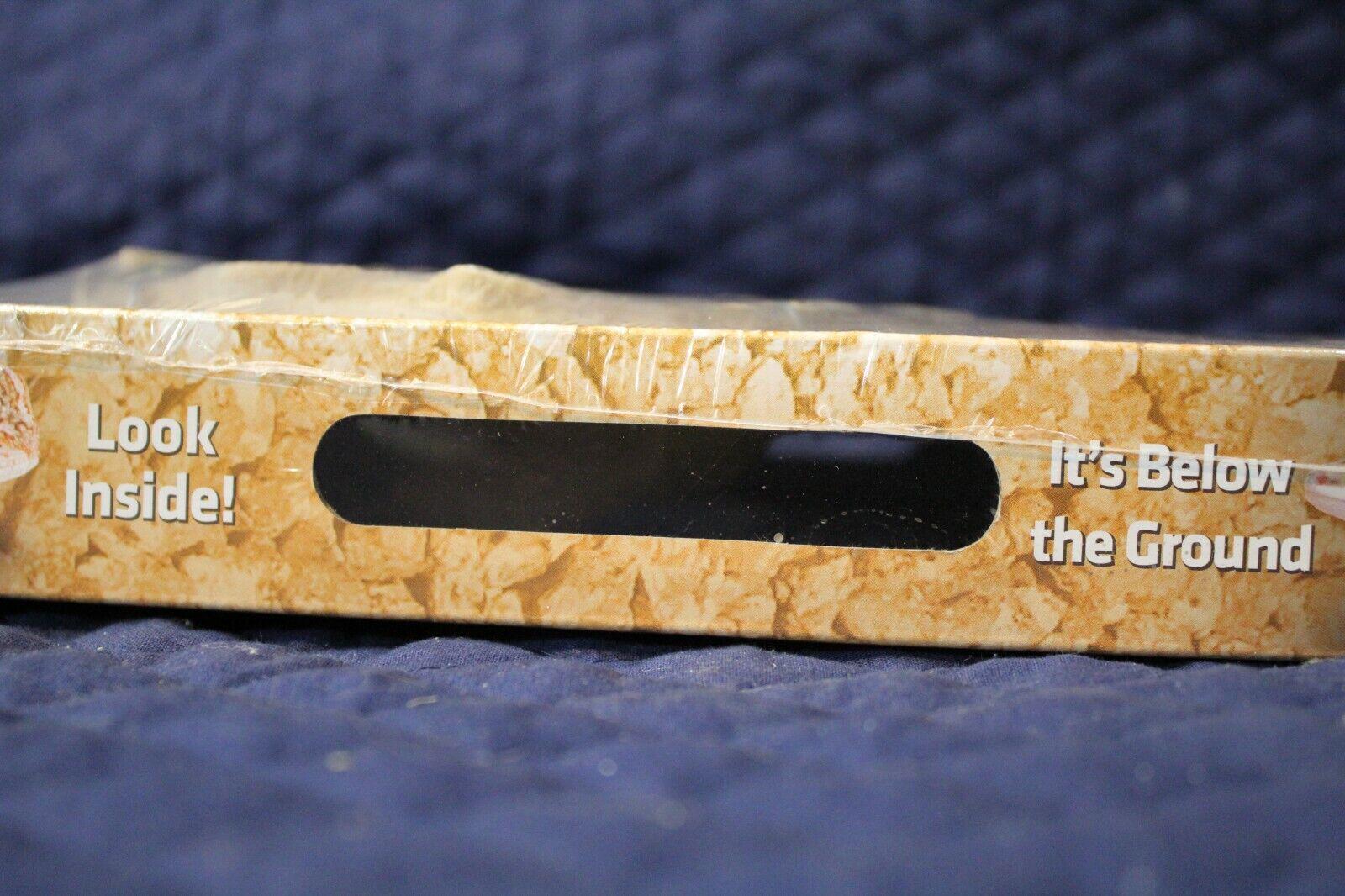 Product packaging for It's Below the Ground with a peek-through window and textured design.