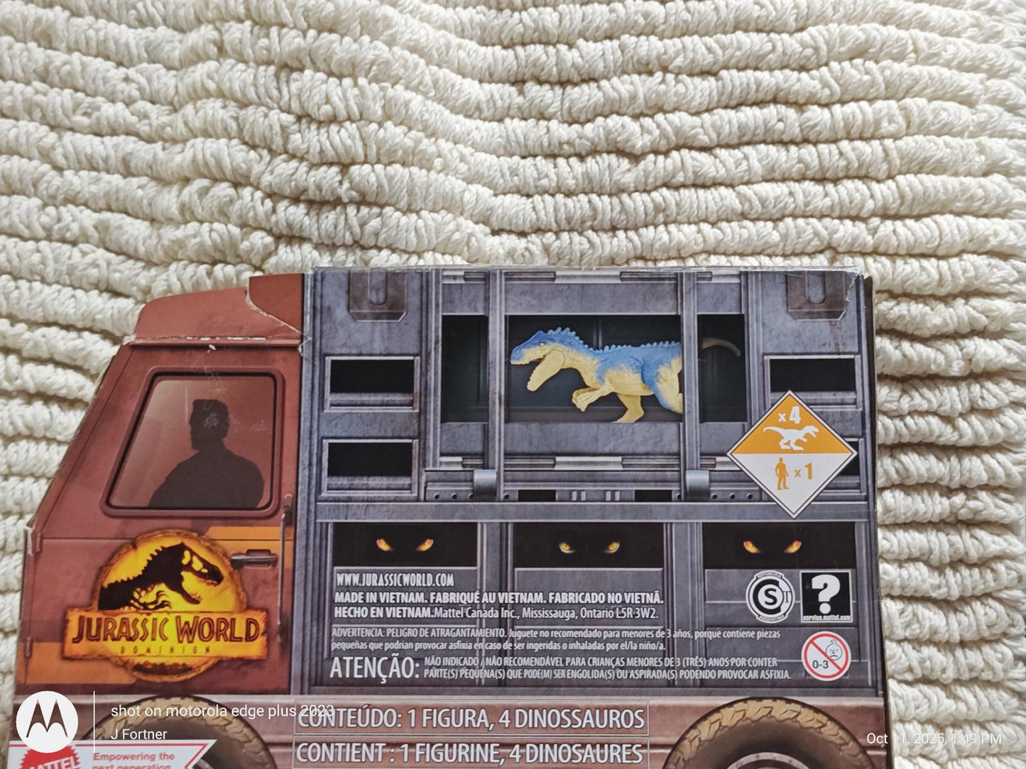 Jurassic World toy truck featuring a dinosaur figure in a cage, detailed design and colors.