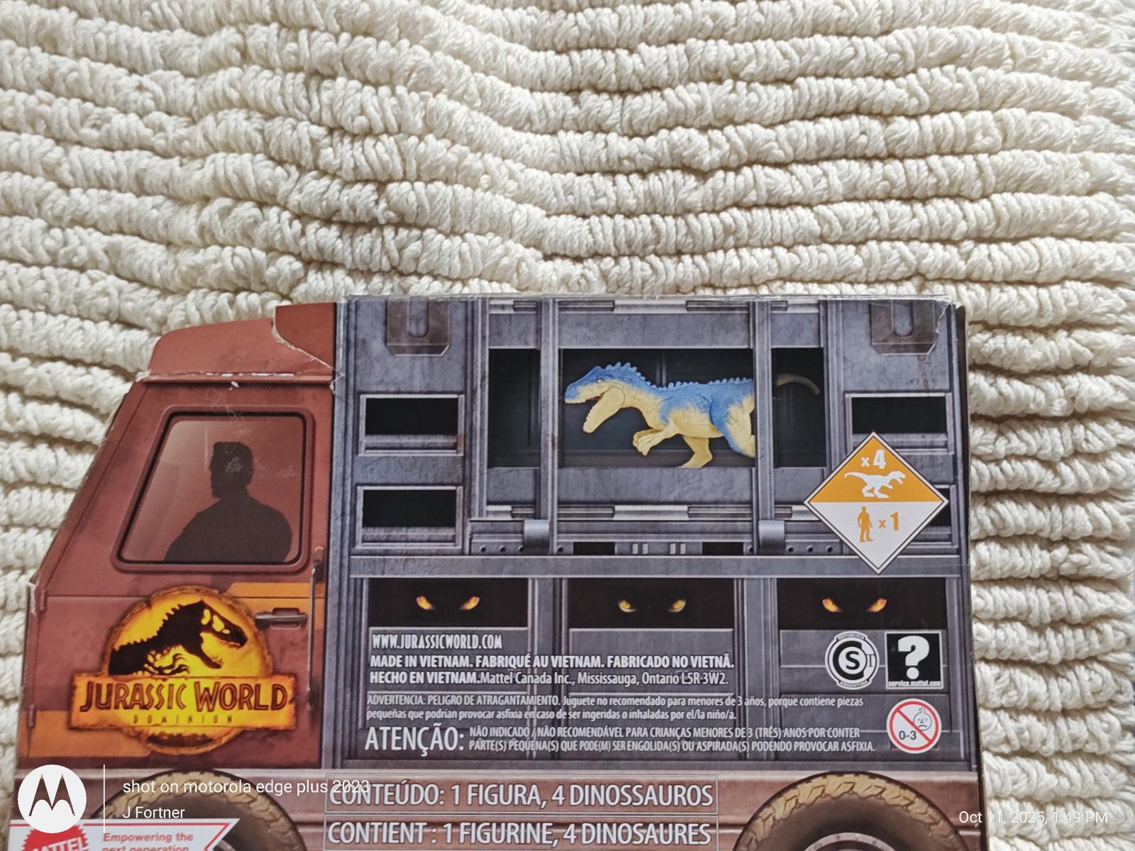 Jurassic World toy truck featuring a dinosaur figure in a cage, detailed design and colors.